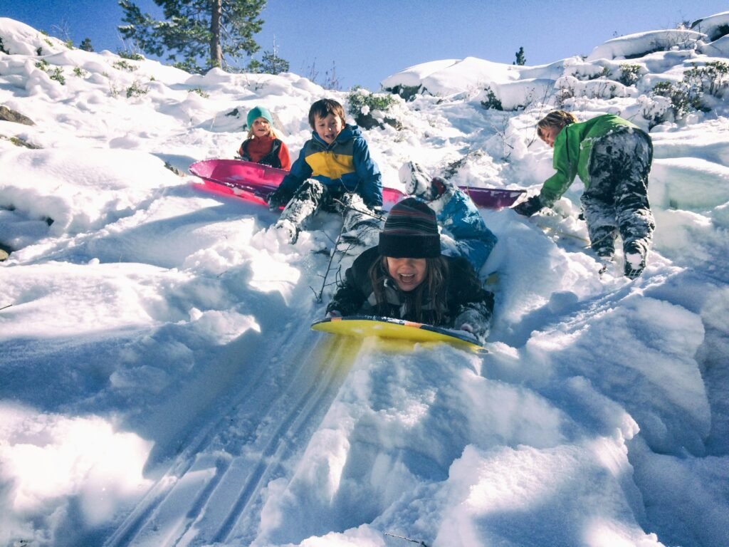 Children sledding down snowy hill.