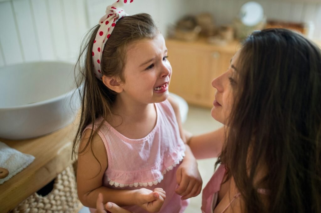 A mother comforts her young daughter while she cries.
