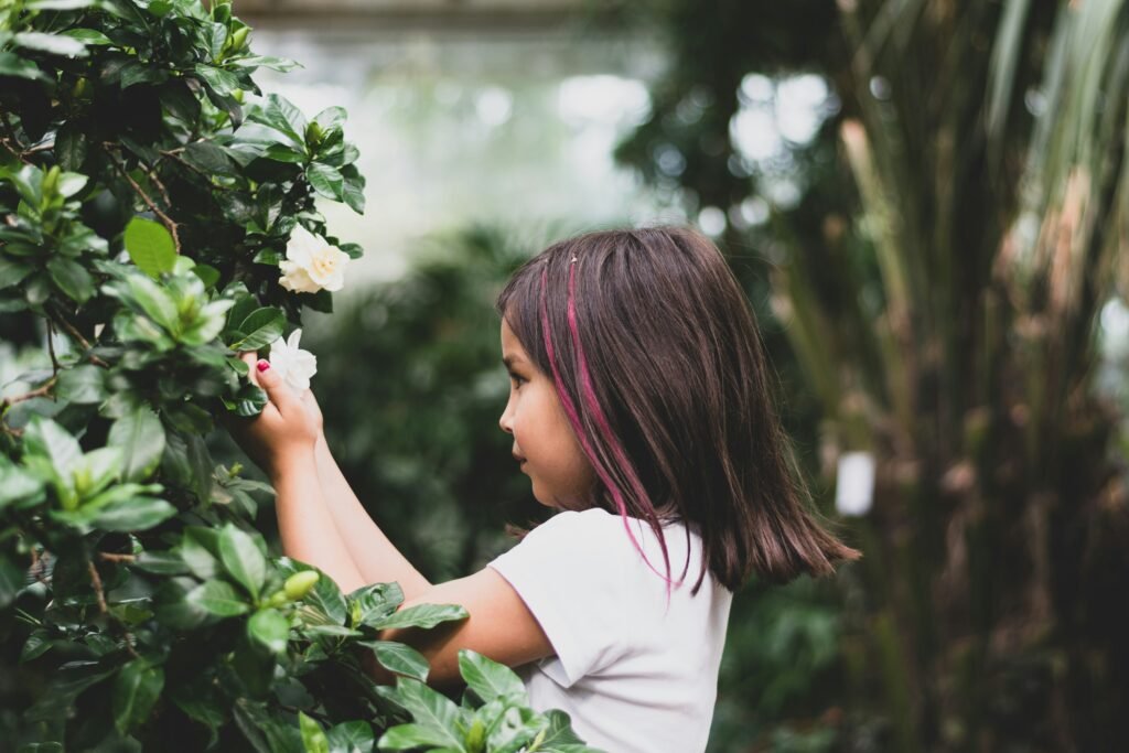 Outdoor adventures with kids—child picking flowers in greenery.