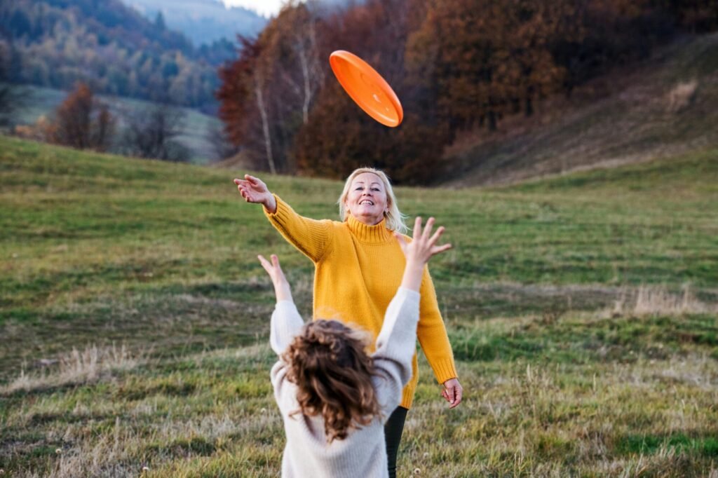 A mother and daughter playing fun outdoor games for kids by playing frisbee 
